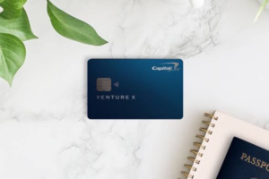 Capital One Venture X card beside a passport and notebook